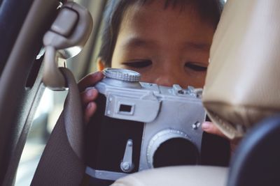 Close-up of boy photographing in car