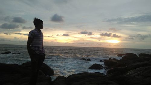 Man looking at sea against sky during sunset