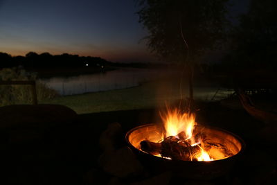 Bonfire in lake against sky at night