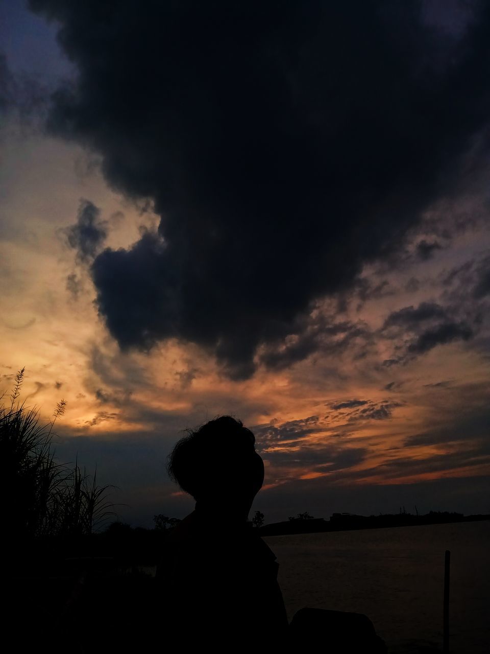 sky, silhouette, cloud, sunset, nature, beauty in nature, one person, water, tranquility, scenics - nature, horizon, evening, dusk, tranquil scene, land, beach, sea, darkness, leisure activity, adult, outdoors, lifestyles, sitting, afterglow, dark, rear view, women, dramatic sky, orange color, men