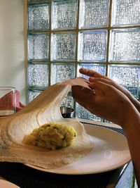 Cropped hands of woman eating thosai in restaurant