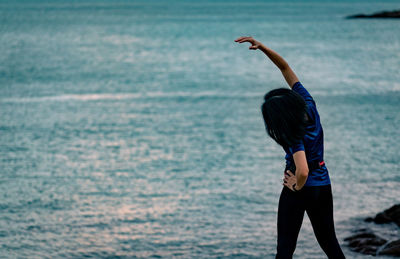 Rear view of woman standing at beach