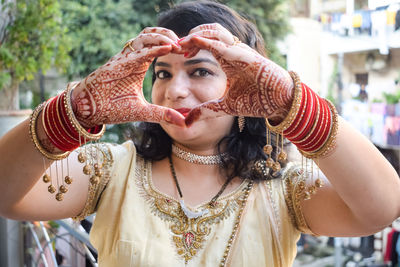 Beautiful woman dressed up as indian tradition with henna mehndi design on her both hands 