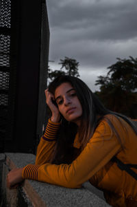 Portrait of young woman sitting against sky