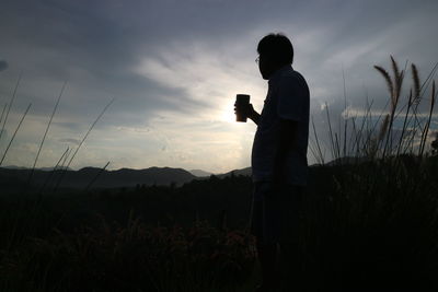 Side view of woman standing against sky during sunset