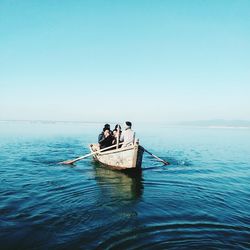 People on boat in sea against clear sky