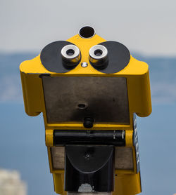 Close-up of yellow coin-operated binoculars against clear sky