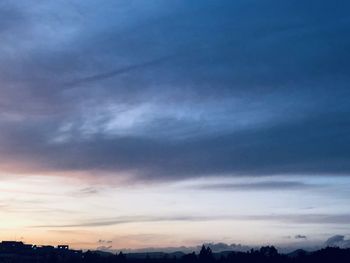 Low angle view of silhouette trees against dramatic sky