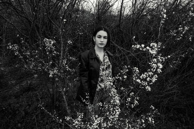 Portrait of woman standing by tree in forest