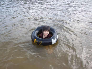 High angle portrait of smiling boy with inflatable ring swimming in lake