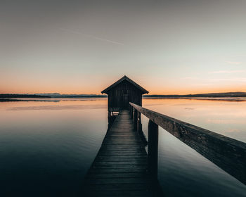Pier over sea against sky during sunset