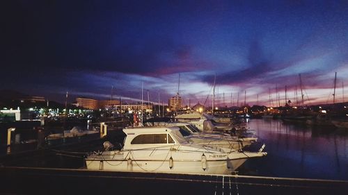 Boats moored on illuminated city against sky at night