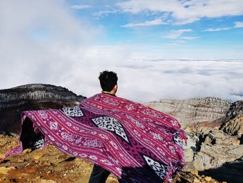 Rear view of man on rock against sky