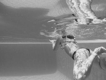 Low section of woman standing in swimming pool