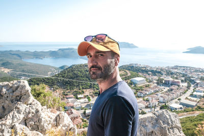 Portrait of young man standing on mountain against sky