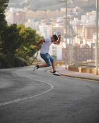 Side view of mature man jumping on road against buildings