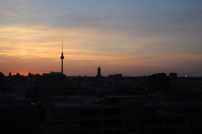 Silhouette of buildings against cloudy sky during sunset