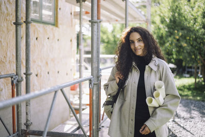 Portrait of young woman standing by railing