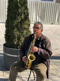 Male street musician playing saxophone on footpath