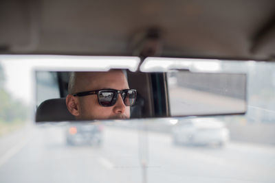 Reflection of man on rear-view mirror of car