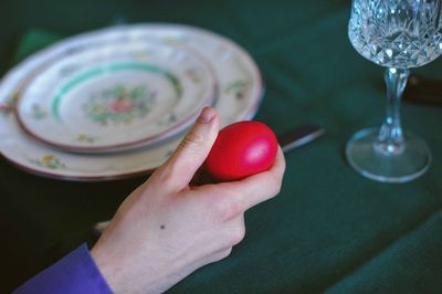 Cropped image of person holding red easter egg at table