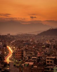 Illuminated cityscape against sky during sunset