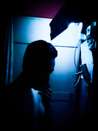 Portrait of young woman standing against illuminated wall at home