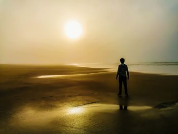 Man standing on beach against sky during sunset