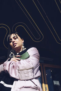 Low angle portrait of young woman standing at entrance of building