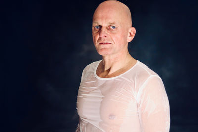 Portrait of man standing against black background