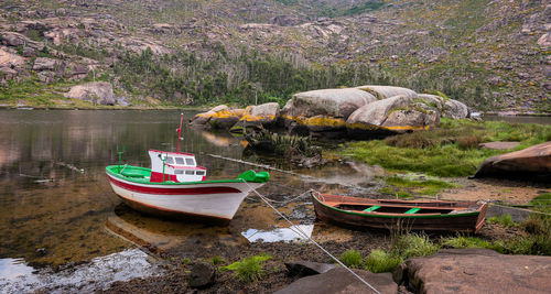 Boats moored on rock by river