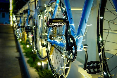 Close-up of christmas lights on bicycles parked by wall at night