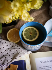 Close-up of tea cup with flowers and book on table