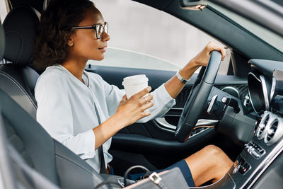 Woman drinking coffee while sitting in car