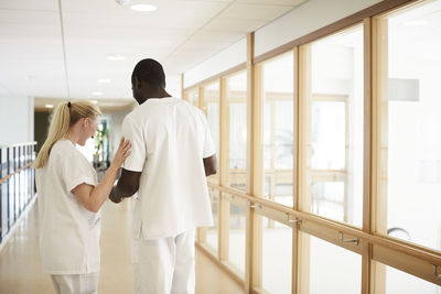Male and female nurse standing at hospital corridor