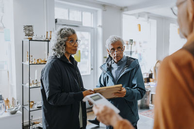 Senior couple buying picture frame and talking with salesman in antique shop