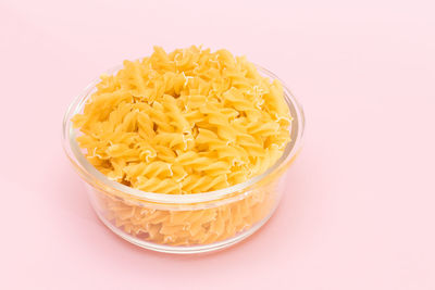 High angle view of pasta in bowl against pink background