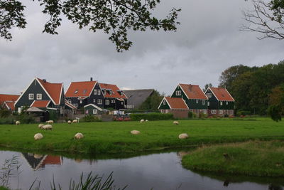 Houses by lake and buildings against sky