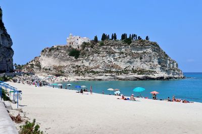People on beach against blue sky