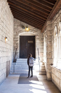 Full length rear view of girl standing in corridor