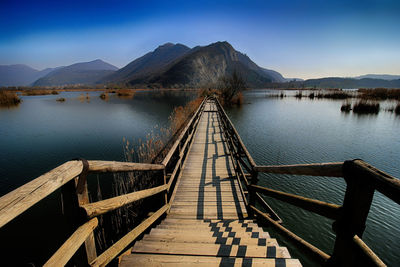 Footbridge over lake leading towards mountains
