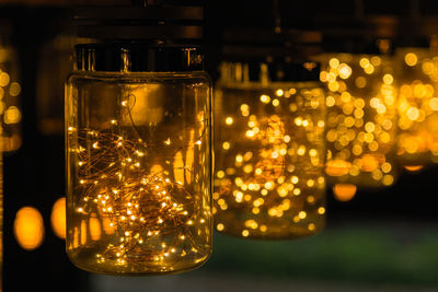 Close-up of illuminated lighting equipment in glass jars on table