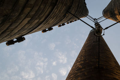 Low angle view of chimneys at industrial building against sky