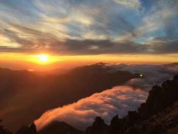 Scenic view of mountains against dramatic sky during sunset