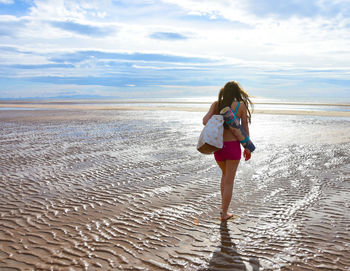 Full length of woman walking at beach against sky