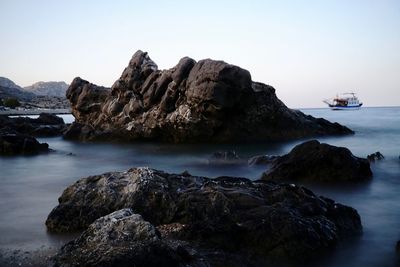 Rock formations on shore against clear sky