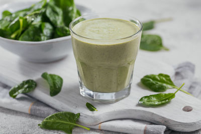 Glass of homemade healthy green smoothie with fresh baby spinach