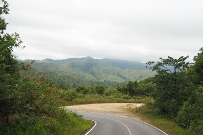 Road leading towards mountains against sky
