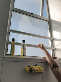 Low angle view of person hand holding glass window