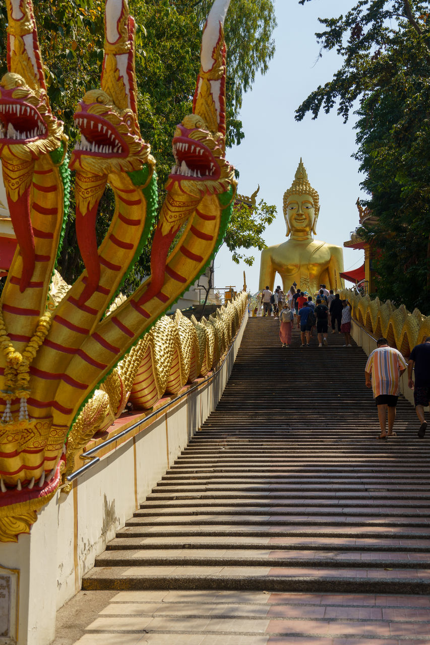 temple - building, religion, belief, architecture, spirituality, built structure, travel destinations, travel, building, place of worship, temple, pagoda, culture, tourism, tradition, nature, gold, history, sculpture, plant, tourist, building exterior, the past, outdoors, group of people, tree, statue, sky, ancient, staircase, shrine, business finance and industry, holiday, city, praying